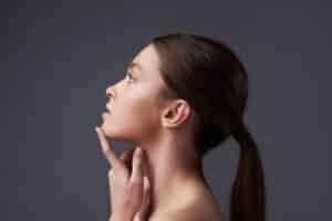 Profile of a woman with a defined chin, illustrating chin augmentation options like implants and dermal fillers.