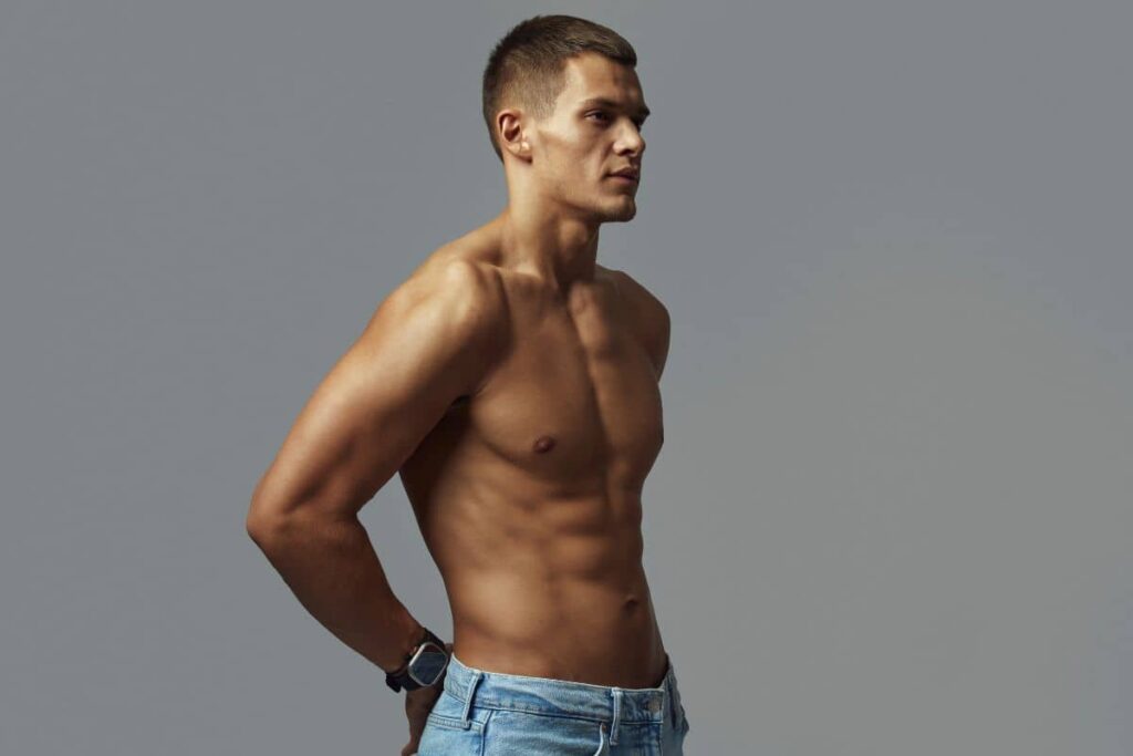 Shirtless man with defined muscles and confident posture showcasing results of male body sculpting procedures