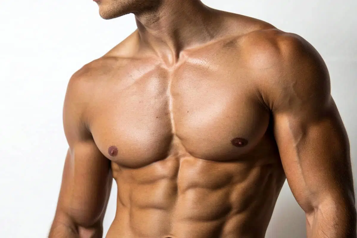 A close-up of a muscular man's torso and chest, highlighting well-defined pectoral and abdominal muscles achieved through bodybuilding and athletic training.