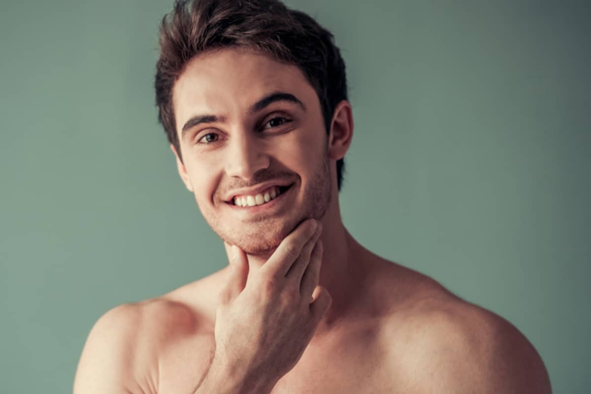 A smiling man touching his chin to highlight a well-defined and projected chin structure.