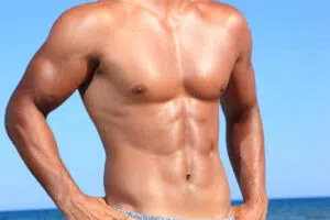 Male torso by the ocean highlighting silicone pectoral implants and chest augmentation safety for men.